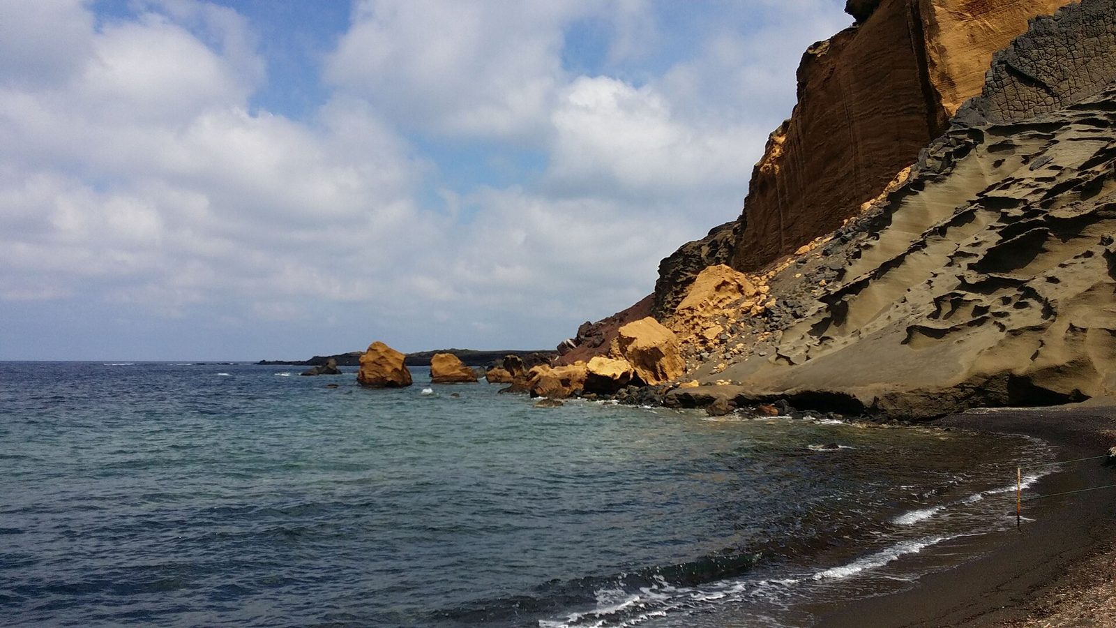 La costa vulcanica di Pozzolana di Ponente a Linosa, con rocce gialle e scure a picco sul mare
