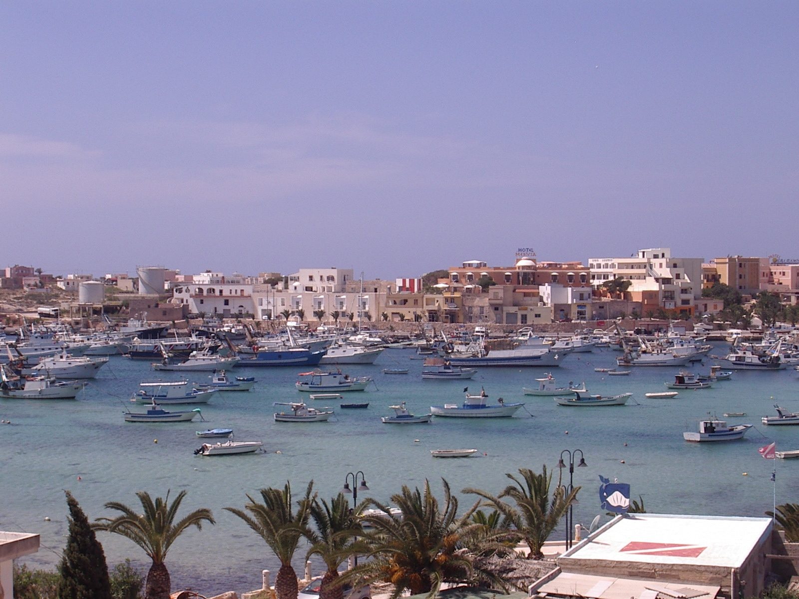 Il porto di Lampedusa con le barche dei pescatori ormeggiate e le case del paese sullo sfondo