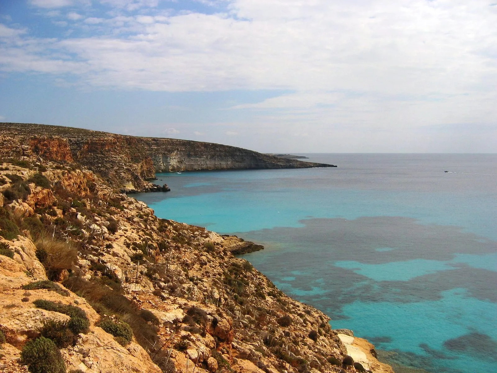 La costa rocciosa di Lampedusa verso Cala Tabaccara, con il mare turchese e i fondali visibili sotto la scogliera