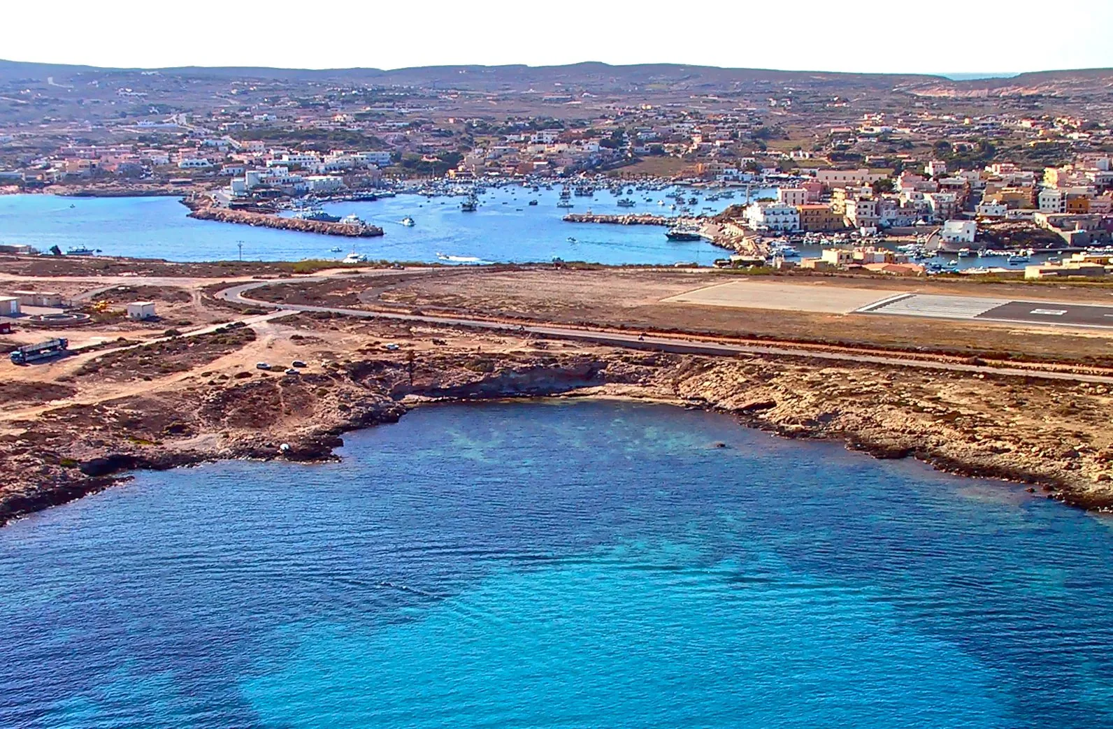Il porto di Lampedusa con le barche ormeggiate e il paese, visti dall'alto