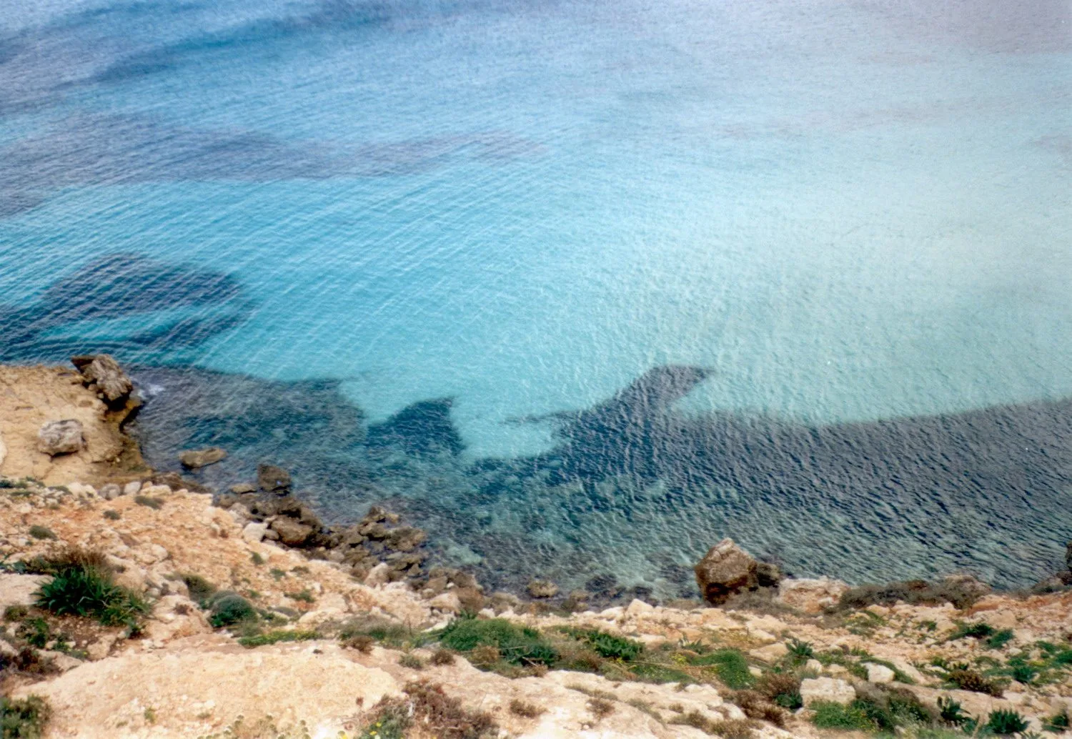 Scogli calcarei e acqua trasparente turchese lungo la costa di Lampedusa